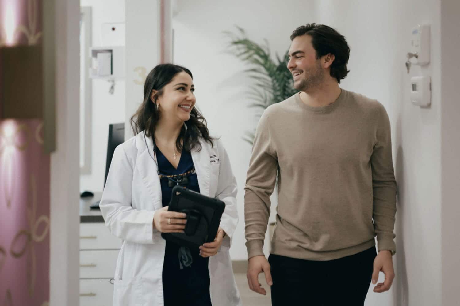 Dr. Josetta DeFrancisco walking with a patient in a clinic hallway, smiling and holding a tablet during a friendly consultation.