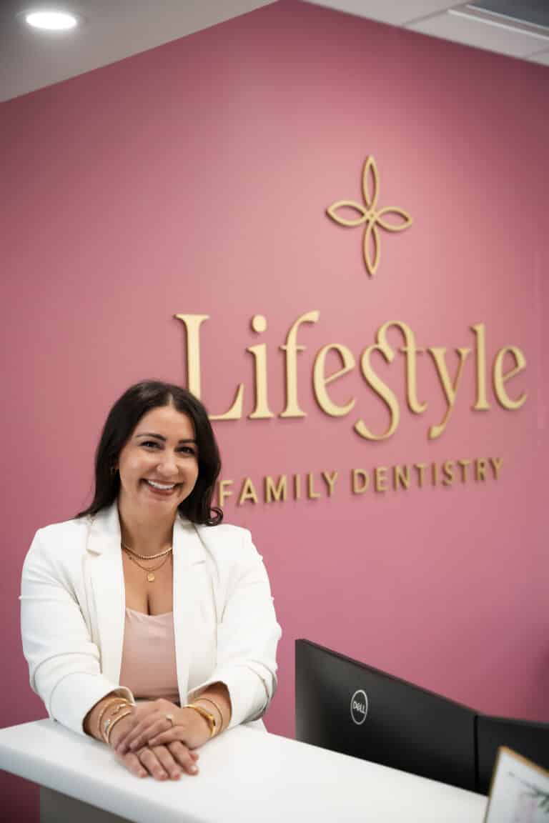 Smiling woman standing in front of a dental office reception area background