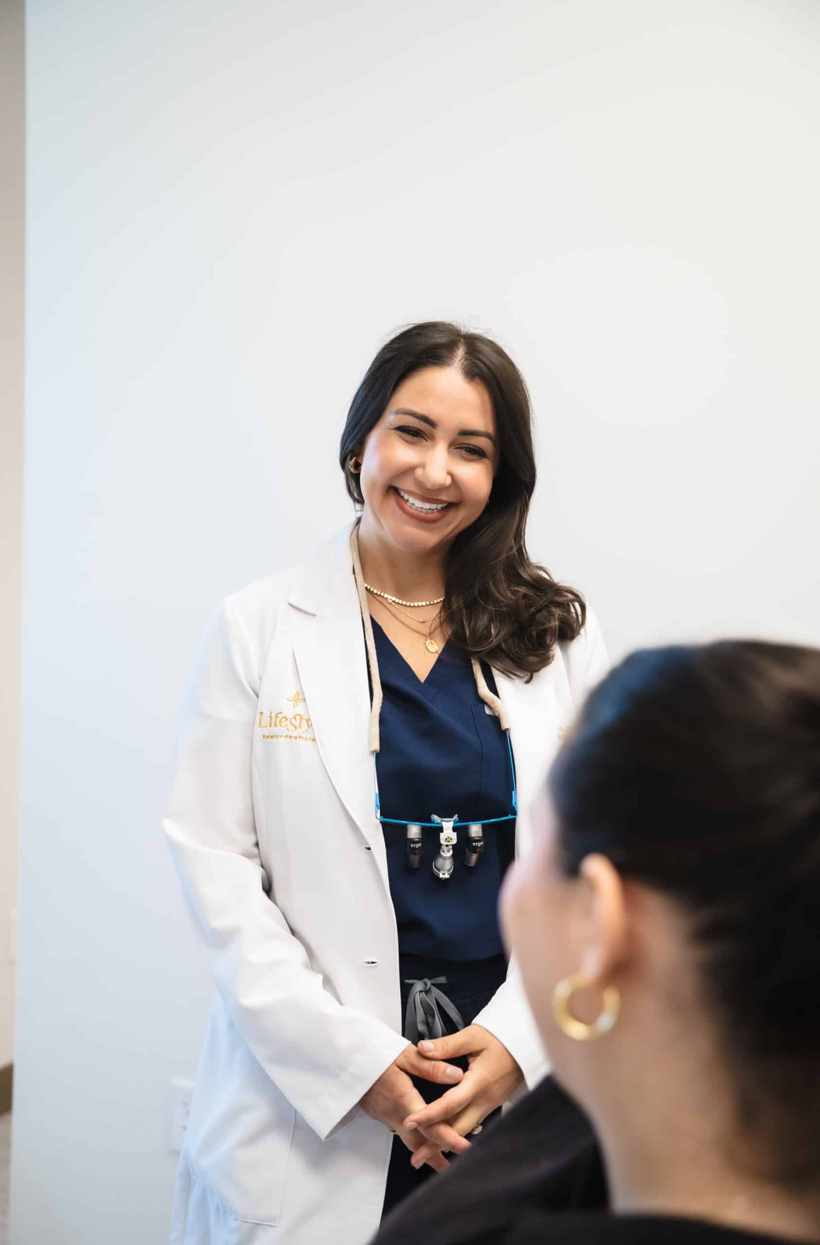 Female dentist showing a smiling male patient his reflection in a handheld mirror